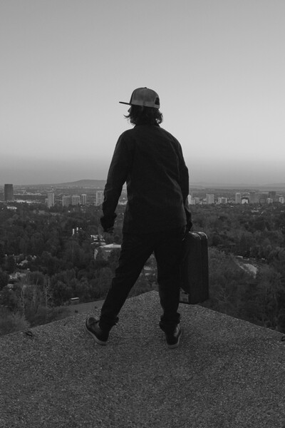 Schwarz-weißes Foto eines Menschen von hinten, der über eine Stadt blickt.