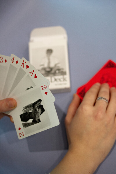 Ein Fotos von H&auml;nden von oben, die Karten des Kartendecks "The Dyke Deck" von Catherine Opie halte.
