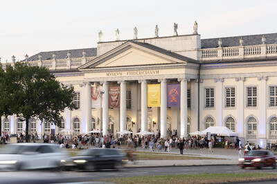 Das Gebäude des Fridericianum von außen, mit vielen Gästen, bei Sonnenuntergang.