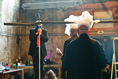 Several people at a performance. Two have soap foam on their heads, a third person has a blue-painted face.