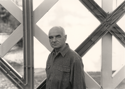 Black and white photograph of Karl Oskar Blase in front of a sculpture