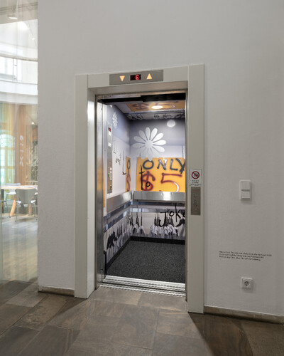 Foto eines Aufzugs im Fridericianum. Er ist von innen mit Fotos und Blumen beklebt.