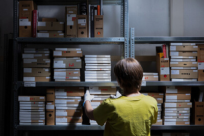 Blick in Performance Art Archiv Die Schwarze Lade; eine Person legt Hand an die Bestände. 