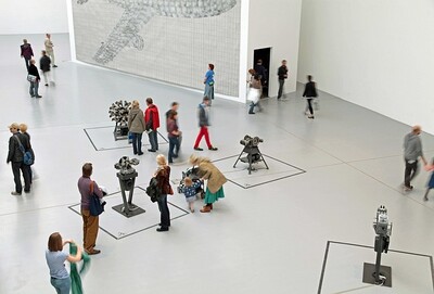 Menschen stehen in einer Ausstellungshalle und sehen sich Kunst an