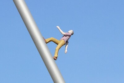 Eine Figur läuft an einer schrägen Stange in den Himmel. Die Figur gehört zu einem Kunstwerk im Freien.