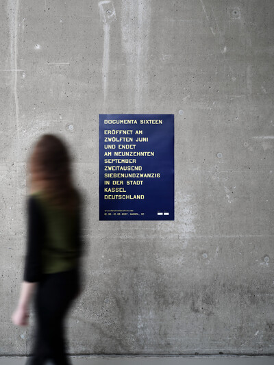 Eine Frau l&auml;uft an einem documenta 16 Plakat vorbei