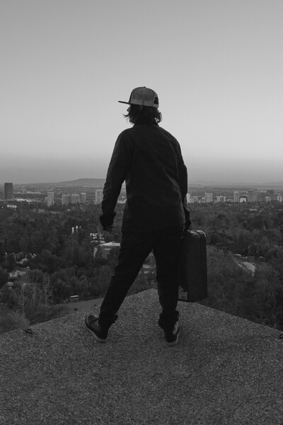 Foto von einer Person, die einen Koffer hält und von oben über eine Stadt schaut.