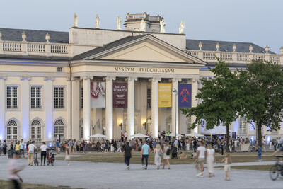 Viele Menschen stehen und sitzen vor dem Fridericianum.