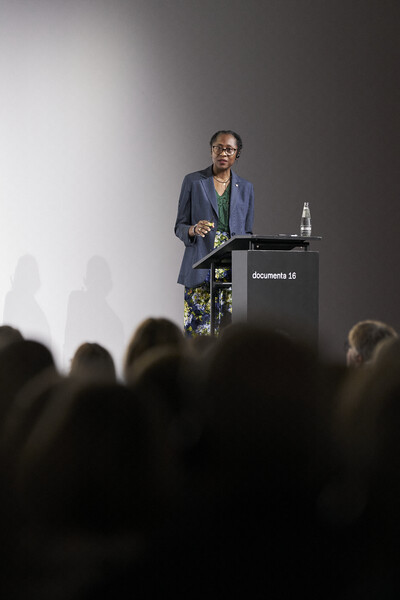 Naomi Beckwith steht auf einer Bühne und hält einen Vortrag.