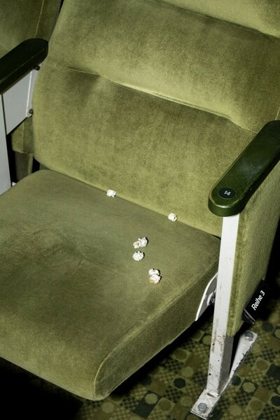Grüner Kinosessel auf dem Popcorn liegt.
