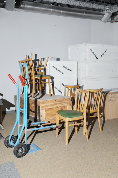 Stühle, eine Sackkarre und große Holzboxen.