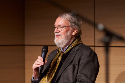 Wulf Herzogenrath bei einer Podiumsdiskussion mit einem Mikrofon in der Hand