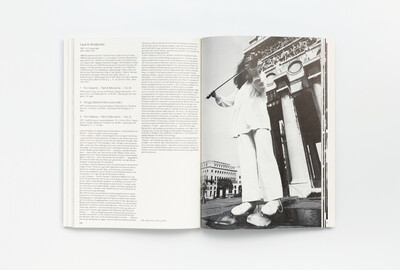 Doppelseite aus dem Ausstellungskatalog der documenta 6 mit Texten zur Künstlerin Laurie Anderson und einer ganzseitigen Schwarzweißfotografie einer Performance vor klassizistischer Architektur.
