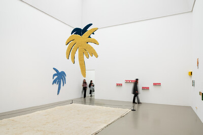 Innenansicht der documenta Halle. Verschiedene Objekte hängen von der Decke und an den Wänden.
