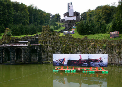 Photographs on a floating platform in the water against the backdrop of the Hercules and Bergpark Wilhelmshöhe.
