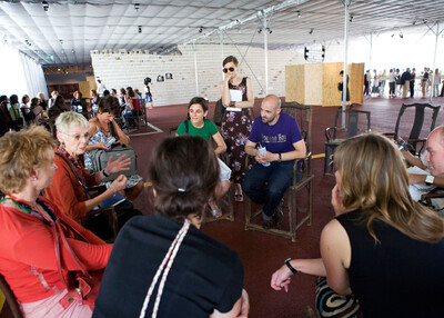 Group of people sitting in an open space and discussing in a circle.