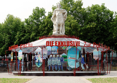 Red and white pavilion with painted panels and red lettering, topped by a large statue.