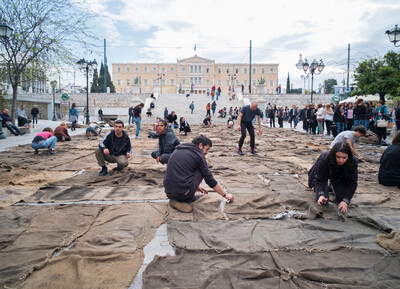 Künstlerische Aktion von Ibrahim Mahama auf dem Syntagma-Platz in Athen. Menschen arrangieren Jutesäcke vor dem griechischen Parlament im Rahmen der documenta 14.