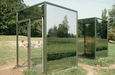 Zwei gläserne Pavillons mit Spiegelwänden stehen in einer Parklandschaft. Im Hintergrund sitzen zwei Personen auf einer Wiese.