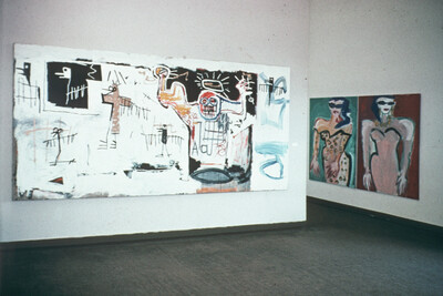 Zwei großformatige Gemälde hängen an den weißen Wänden eines Ausstellungsraums. Links ist eine expressive, figurenreiche Komposition mit Textfragmenten und einem stilisierten Totenkopf zu sehen, rechts zwei abstrahierte Figuren mit betonten Körperformen.