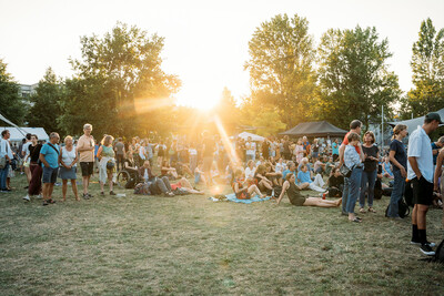 Ein entspanntes Outdoor-Event mit Menschen, die auf einer Wiese im Sonnenlicht verweilen.
