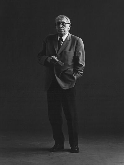 Black and white photograph of Arnold Bode. He is standing in an exhibition space, possibly in a conversation or on a guided tour.