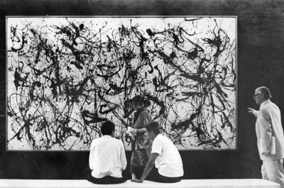Menschen sitzen und stehen vor einem Gemälde von Jackson Pollock.