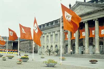 Vorplatz des Fridericianum. Es wehen Fahnen der documenta 2. Die Prtikus ist mit Bannern geschmückt.